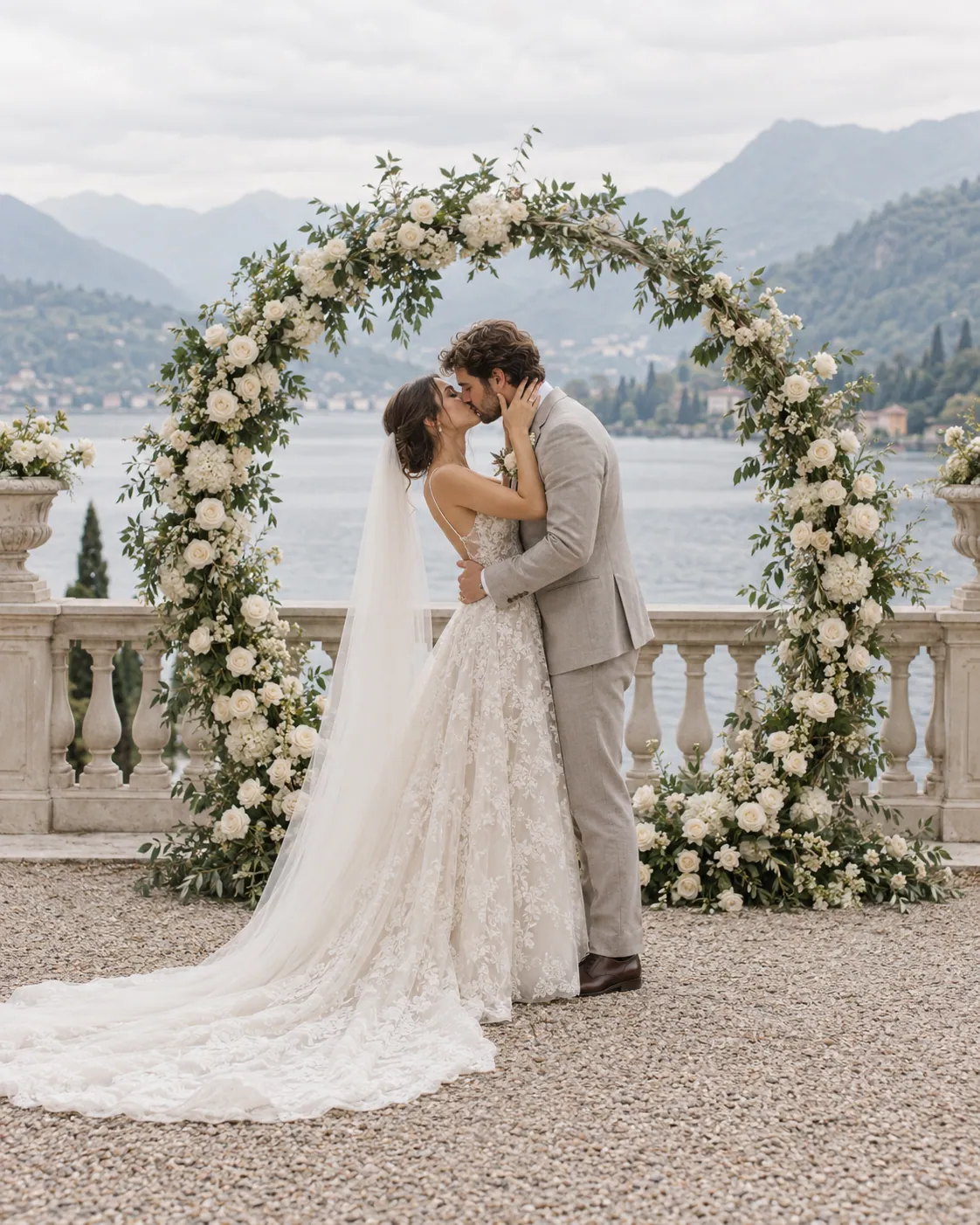 Sposi che si baciano sotto un arco di rose su una terrazza sul lago